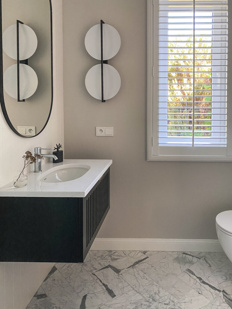 widok na okno z shuttersami i konsolke w łazience